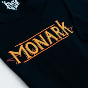 Zoom sur la face typographie de Monark à l'avant du t-shirt Emissaire Noir, l'Etiquette de col est visible et représente un M blanc cyberpunk