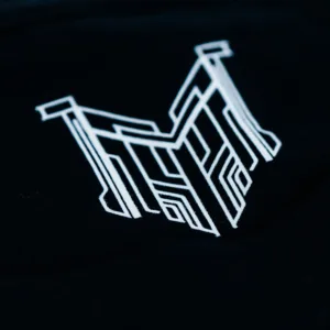 Zoom sur l'étiquette de col du t-shirt Emissaire noir, qui représente un M cyberpunk blanc